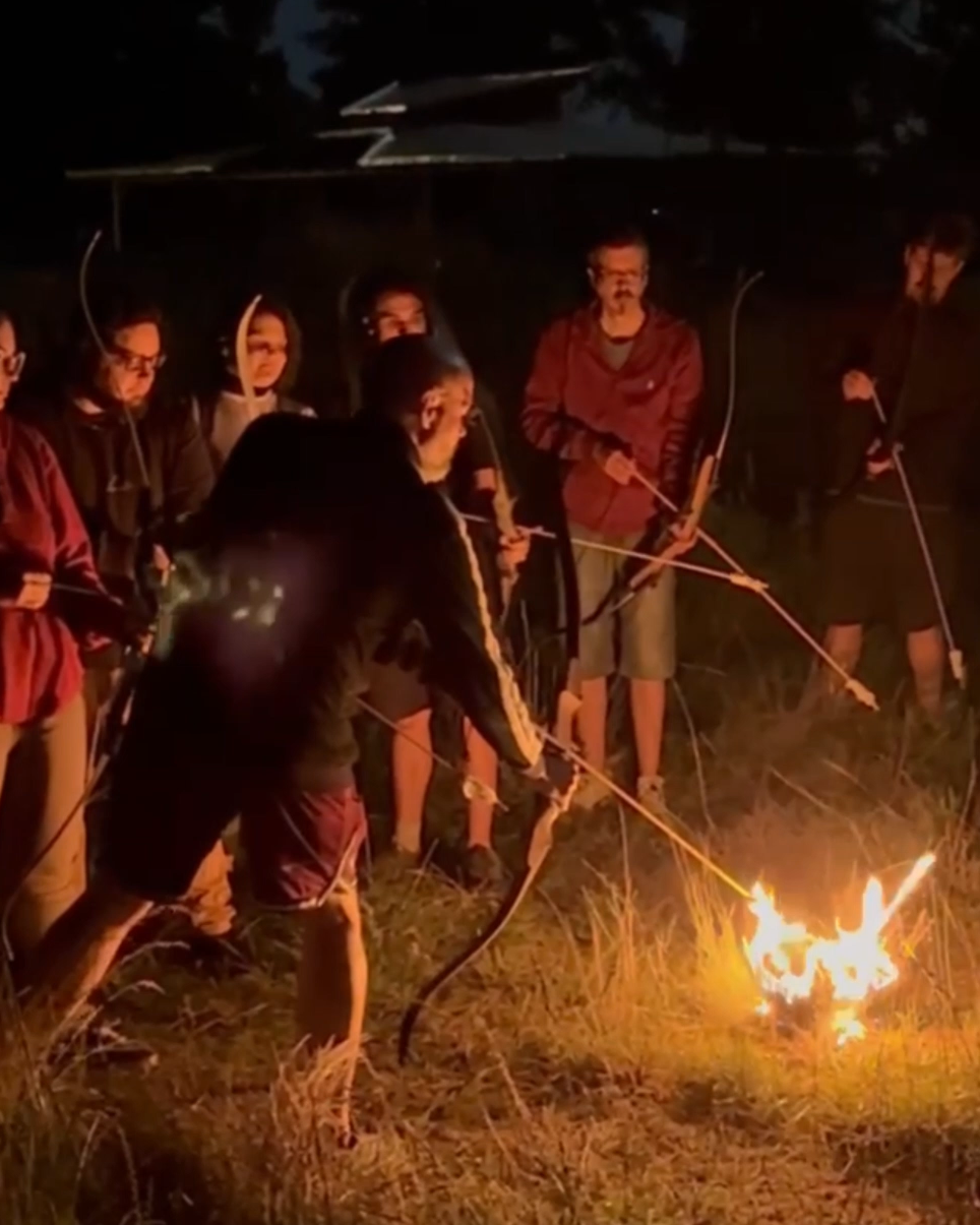 personas haciendo arquería con flechas de fuego